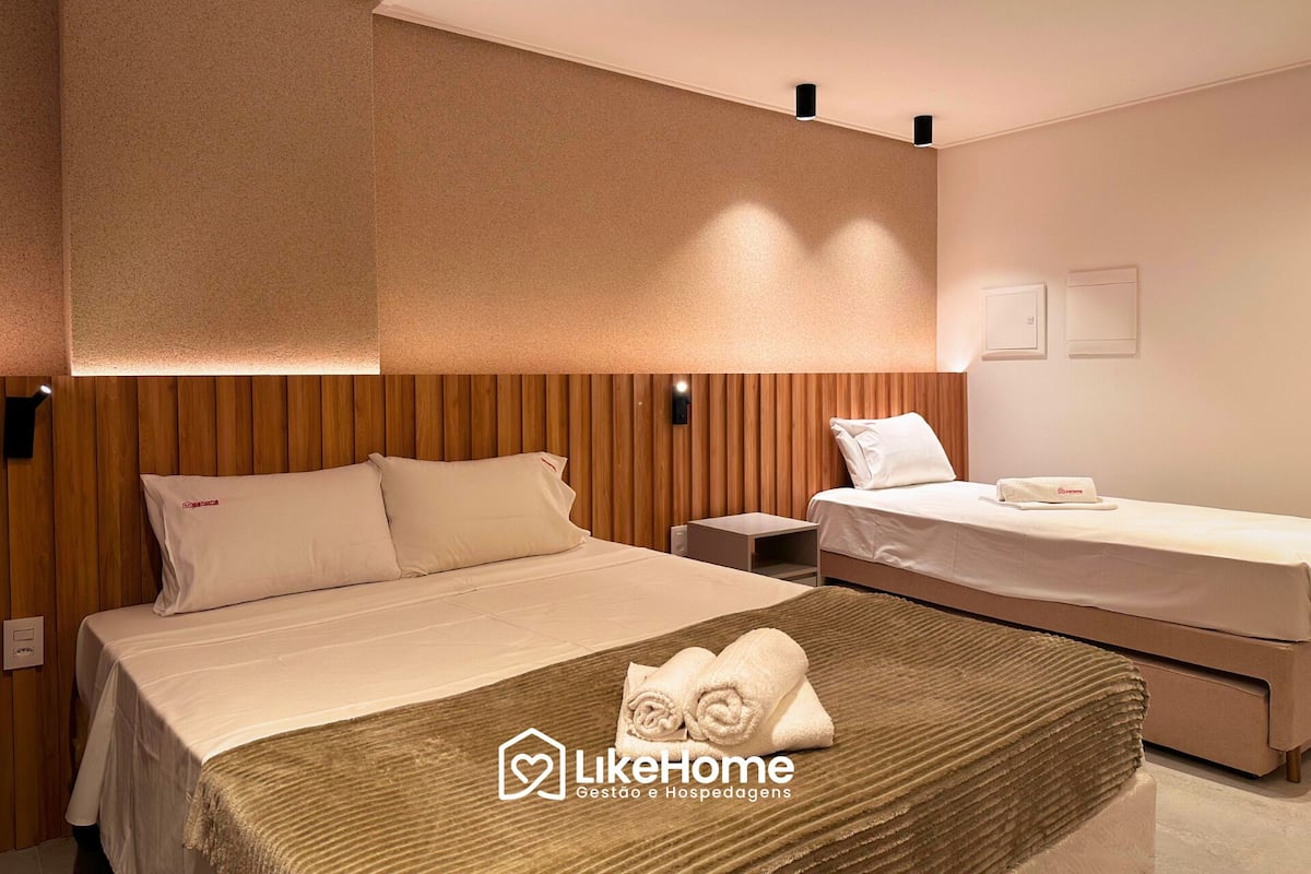 Una habitación de hotel con dos camas, cabecera de madera y pared con textura.