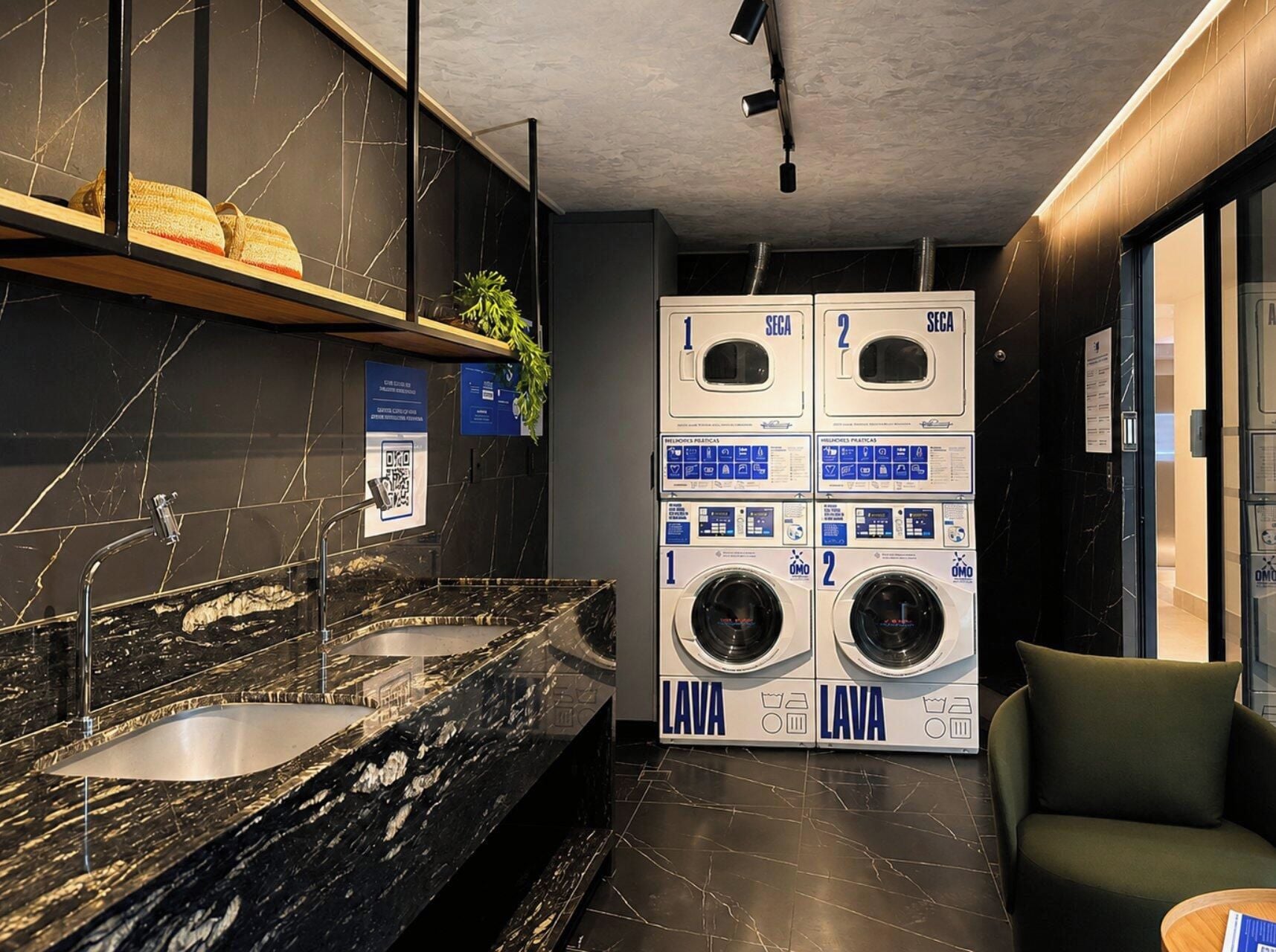 Une salle de bain moderne avec un lavabo en marbre, deux machines à laver et une chaise verte.