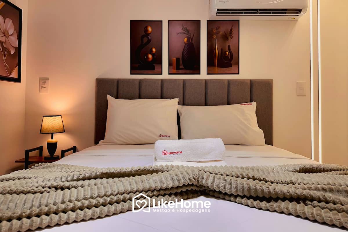 Una habitación de hotel con una cama, una mesita de noche con lámpara y tres obras de arte en la pared sobre la cama.