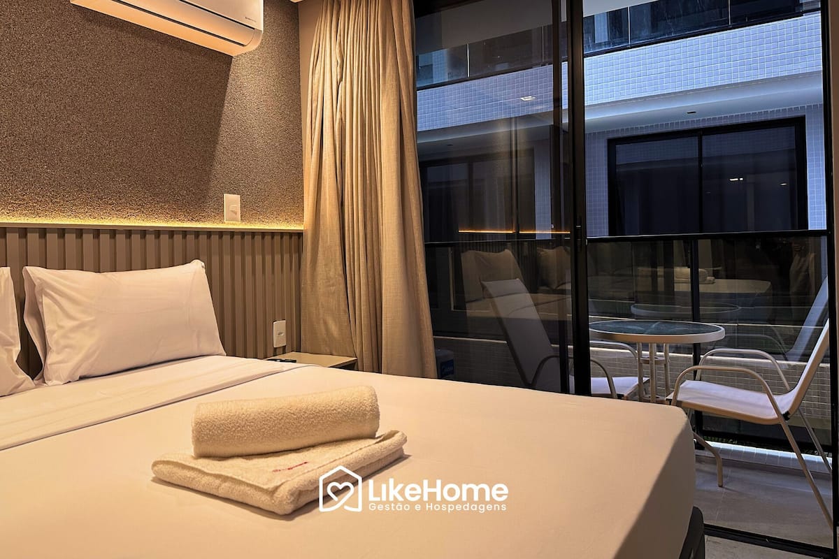 Habitación de hotel con cama, ventana con cortinas y vistas al exterior, además de una pequeña mesa con sillas.