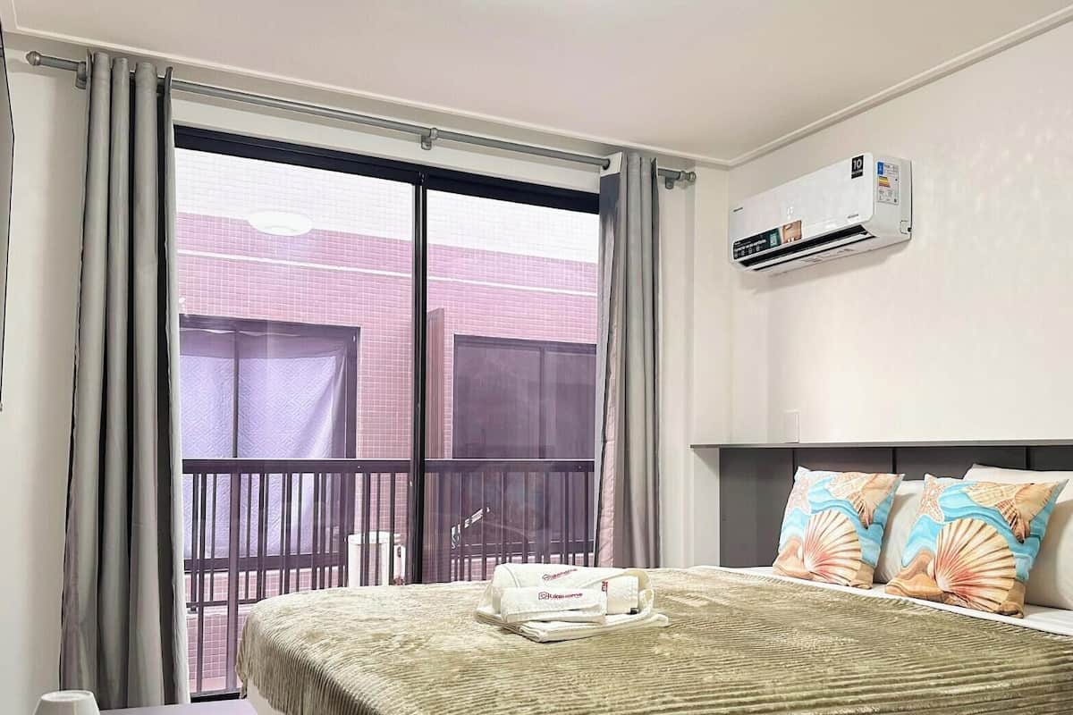 Habitación de hotel con cama, balcón, aire acondicionado y televisor.