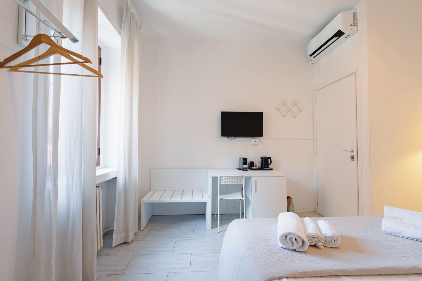 A hotel room with a bed, a desk, a chair, a TV, and a coffee maker.