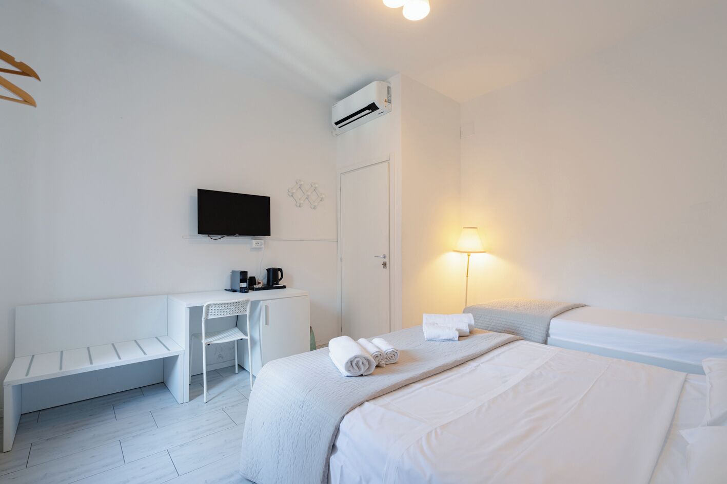 A hotel room with a bed, a desk, a chair, a TV, and a lamp.