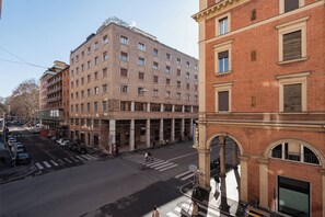 A multi-story building with a central courtyard, large windows, and a pedestrian crossing. - CENTRALE BOLOGNA (Bologna)