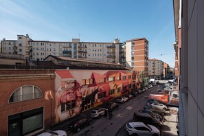 A street view with parked cars, a mural on a building, and multiple-story residential buildings in the background. - CENTRALE BOLOGNA (Bologna)