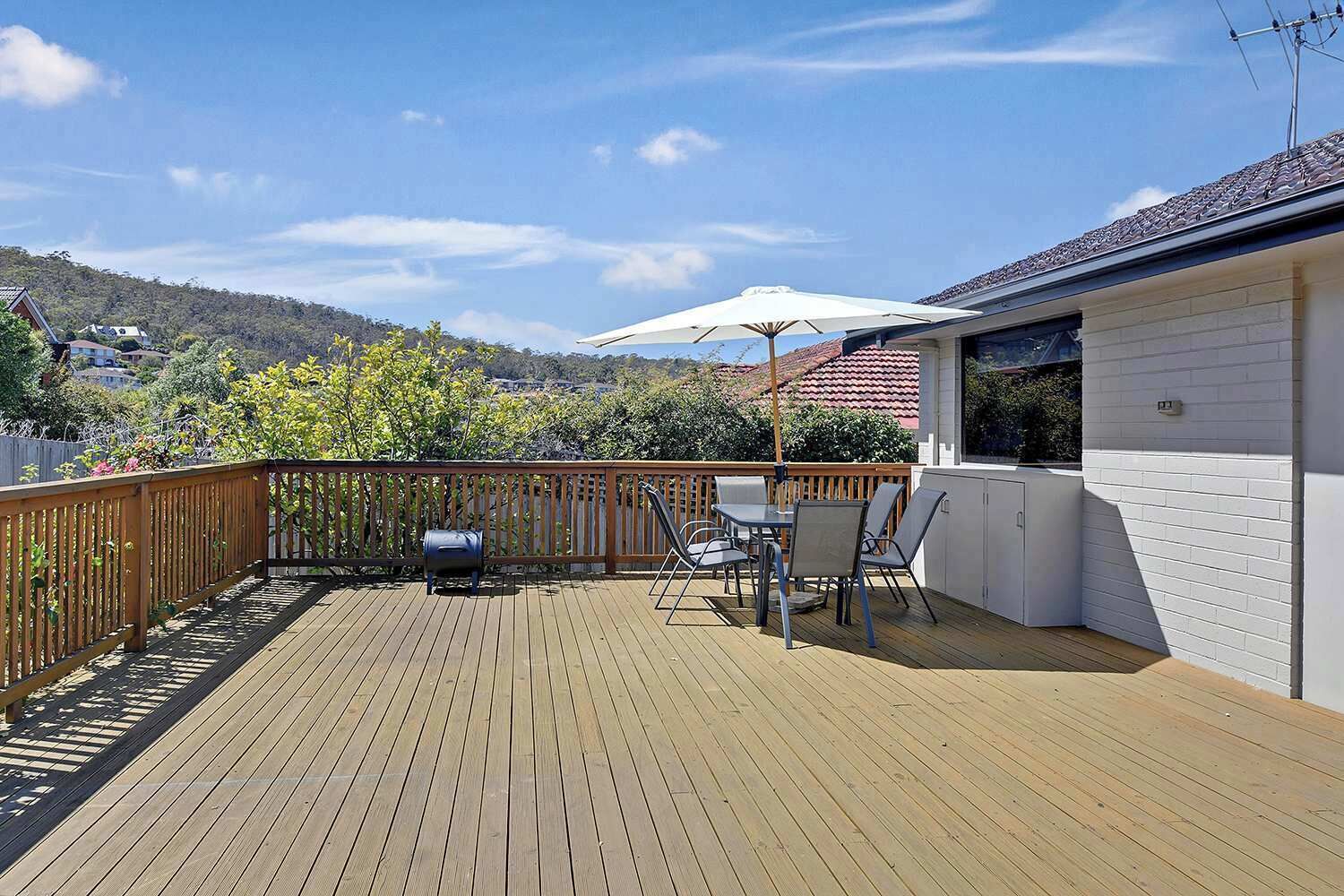 A wooden deck with outdoor furniture and a barbecue grill.