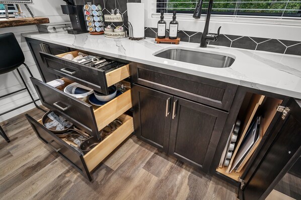 A modern kitchen with a built-in sink, dark wooden cabinets, and a marble countertop.