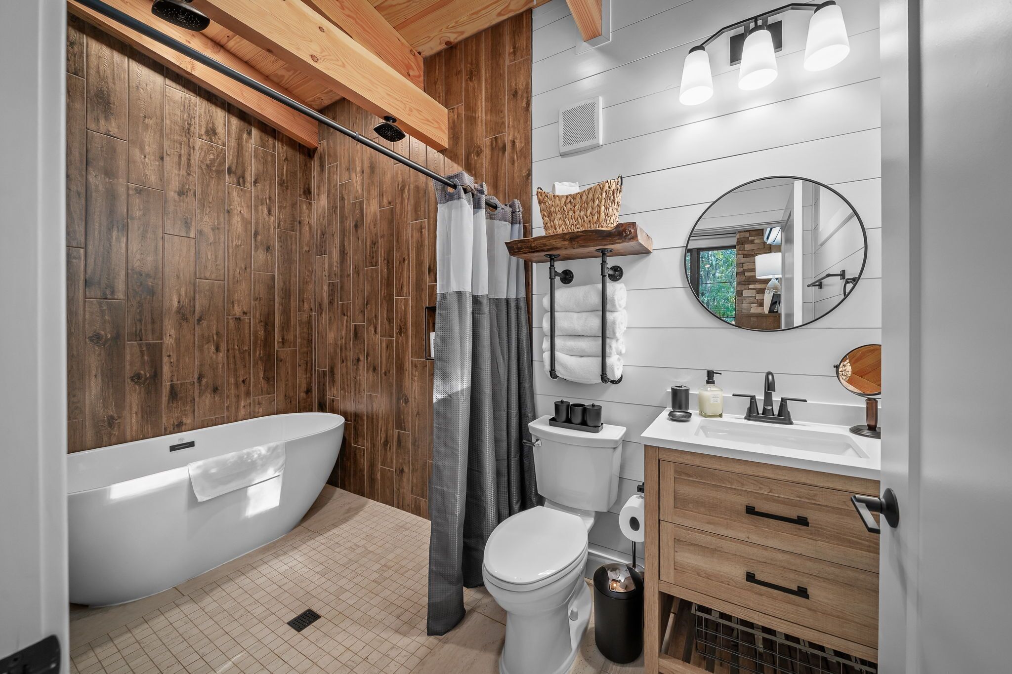 A modern bathroom with a wooden floor, a white bathtub, a toilet, and a vanity with a mirror.