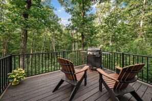 A deck with a grill, two chairs, and a potted plant. - NEW - Treehouse - Dogwood (Jonesburg)