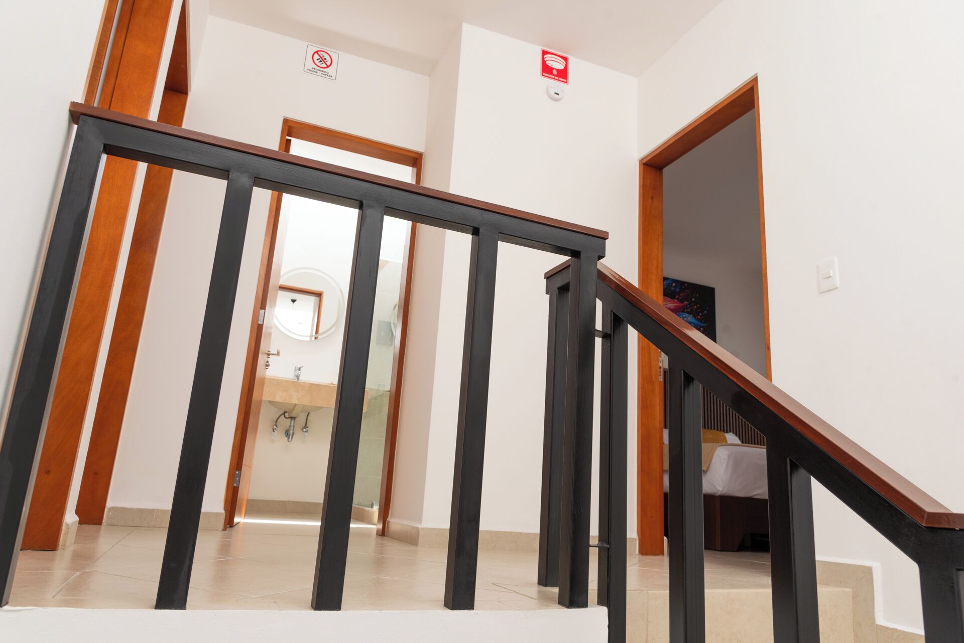 A staircase with wooden handrails and a mirrored wall.