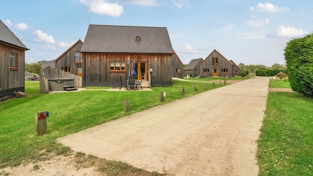 Un bâtiment rustique en bois, doté d’un porche, d’un petit espace extérieur aménagé pour s’asseoir et surplombant un ciel dégagé.