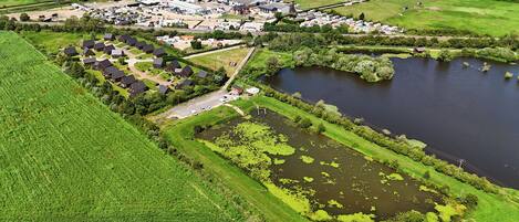 Une vue aérienne d’une zone rurale avec une étendue d’eau importante, une petite île et un ensemble de bâtiments auxquels mène une route.