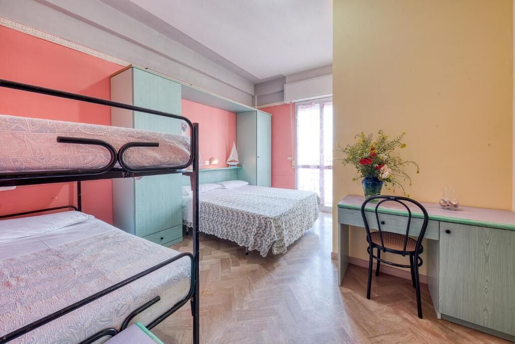 A dormitory room with bunk beds, a desk, and a chair.