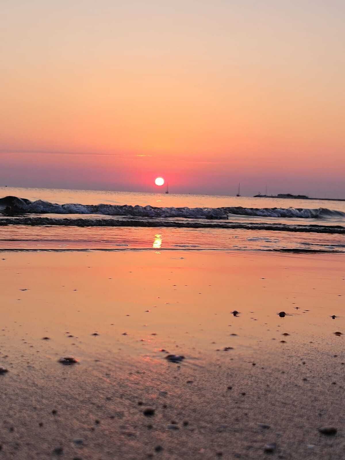 Een strand bij zonsondergang met golven en een heldere lucht.