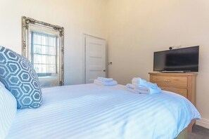 Quarto de hotel com cama, televisão, guarda-roupa e porta.