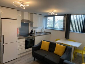 A compact kitchen with a built-in oven, a sink, and a dining area with a table and chairs.