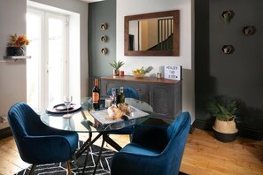A dining area with a glass table, blue chairs, a mirror, and a sign on the wall.