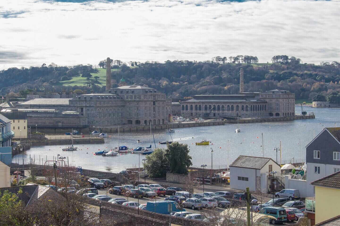 A coastal town with a prominent historic building, a marina with boats, and a parking area.