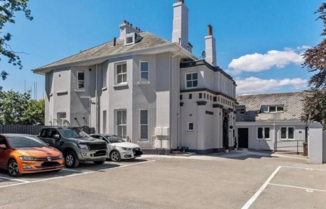Um edifício de dois andares com um estacionamento à frente.