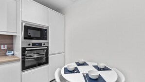 Una cocina moderna con electrodomésticos integrados, una mesa redonda con cuatro cuencos blancos y cubiertos, y una encimera de madera.