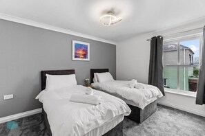 Quarto de hotel com duas camas, um quadro na parede e uma janela com cortinas.