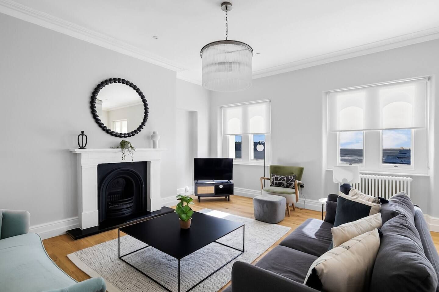 Un salon moderne avec une cheminée, un téléviseur, un canapé et une vue sur la mer grâce à de grandes fenêtres.