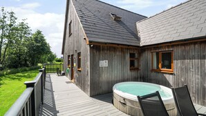 A wooden building with a hot tub, a deck, and a fenced garden area. - Lodge 13 - Hazelnut (Brigg)
