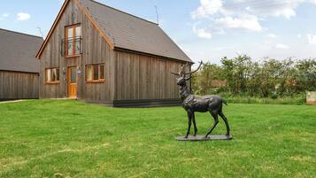 A wooden building with a sloped roof and a statue of a deer in front.