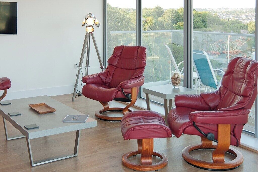 Une pièce moderne avec deux fauteuils en cuir rouge, une petite table et un lampadaire.