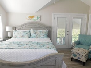 A bedroom with a bed, a chair, a door, and a window.