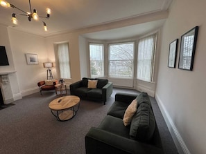 A living room with a fireplace, a round wooden coffee table, two sofas, and a television. - 2 bed Lower Deck Wilderness Hse by Smart Welcomes (Plymouth)