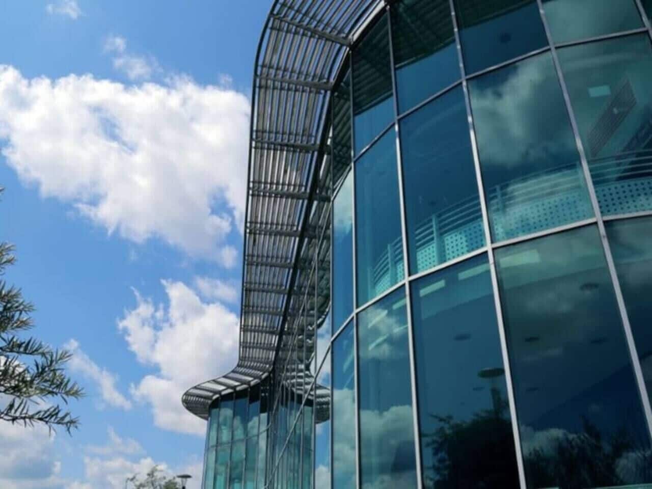 A modern building with a curved glass facade and metal framework.