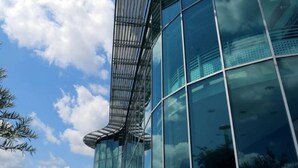 Un edificio moderno con fachada de vidrio curvo y estructura metálica.