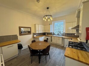 A modern kitchen with a dining table, built-in appliances, and a window providing natural light. - 2 bed Lower Deck Wilderness Hse by Smart Welcomes (Plymouth)