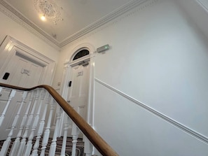 A staircase with white balusters and a wooden handrail leading to a door with a small sign above it. - 2 bed Lower Deck Wilderness Hse by Smart Welcomes (Plymouth)