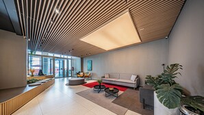 Un hall d’entrée moderne avec un comptoir d’accueil, un espace salon et de grandes fenêtres.