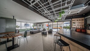 Un intérieur moderne avec un bar, des espaces aménagés pour s’asseoir et une vue sur l’extérieur.
