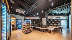 Un intérieur moderne avec un plancher en bois, un espace salon central doté d’une table et de chaises, ainsi que des étagères où sont exposés divers objets.