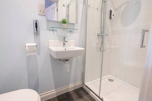 A modern bathroom with a glass shower enclosure, a white sink, and a small potted plant on the countertop. - Single Room @ Ocean Stays by Smart Welcomes (Plymouth)