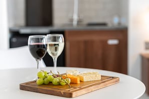 Ein Tisch mit einer Holzplatte, auf der Käse, Trauben und zwei Weingläser stehen.