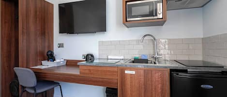 A compact kitchenette with a microwave, sink, and a small refrigerator.