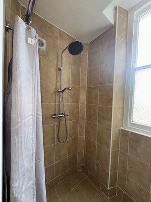 A shower with a handheld showerhead, a wall-mounted faucet, and a shower curtain. - 2 Bed - The Poop Deck by Smart Welcomes (Plymouth)
