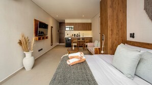 Una habitación de hotel moderna con cama, un pequeño escritorio, kitchenette y baño.