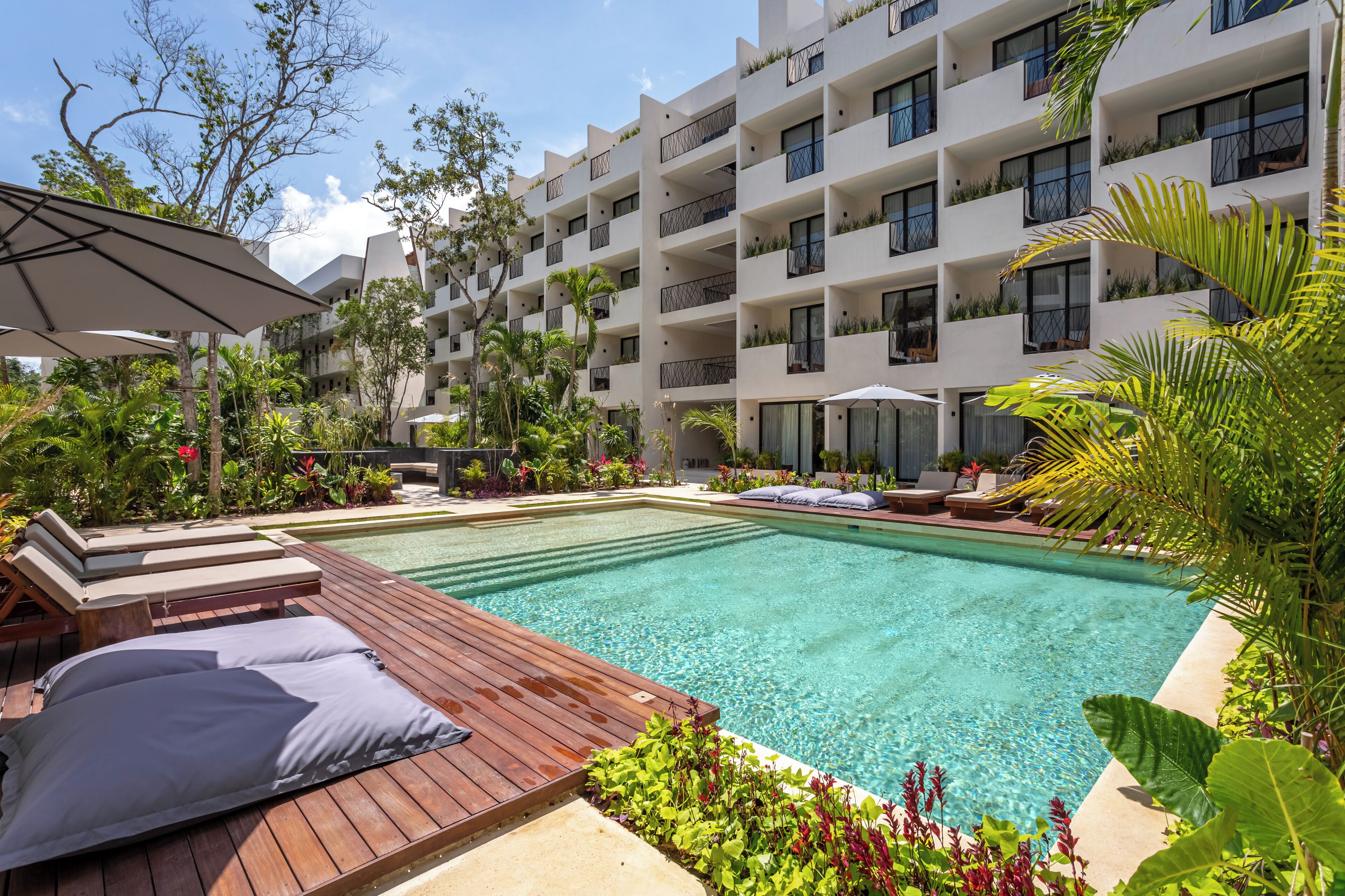 Un espace piscine d’hôtel doté d’une terrasse en bois, de chaises longues et d’une piscine à l’eau d’un bleu cristallin.