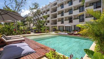 Un espace piscine d’hôtel doté d’une terrasse en bois, de chaises longues et d’une piscine à l’eau d’un bleu cristallin.