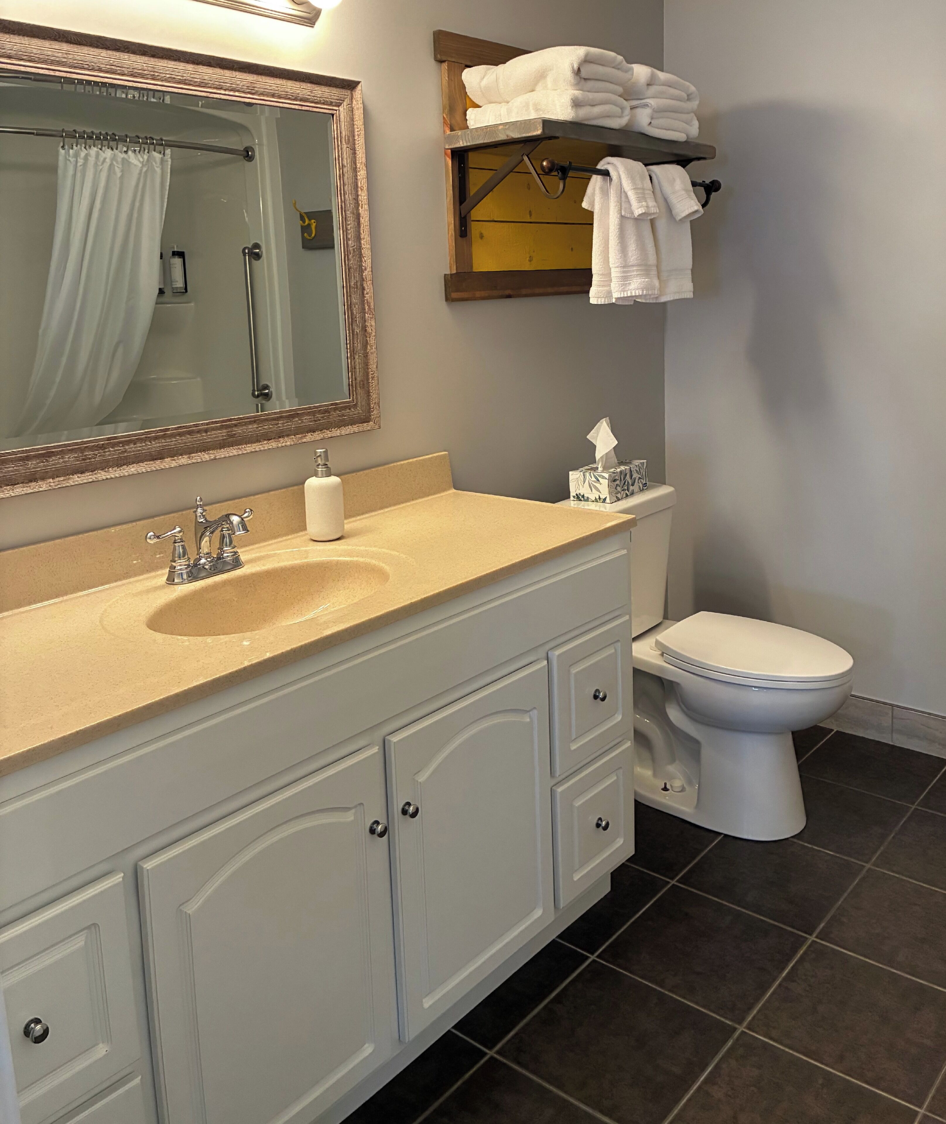 A bathroom with a sink, mirror, towel rack, toilet, and a tissue box.