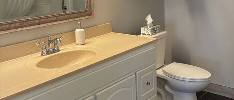 A bathroom with a sink, mirror, towel rack, toilet, and a tissue box.