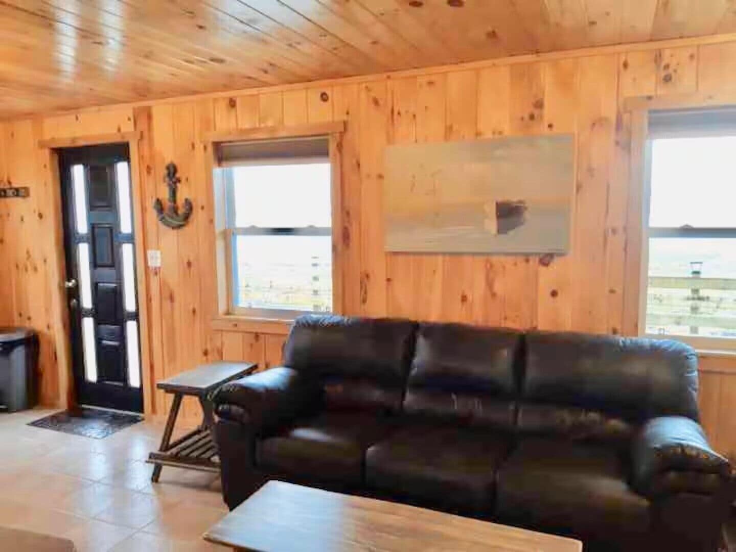 Un intérieur en bois avec un canapé en cuir, une petite table et une porte donnant sur l’extérieur.