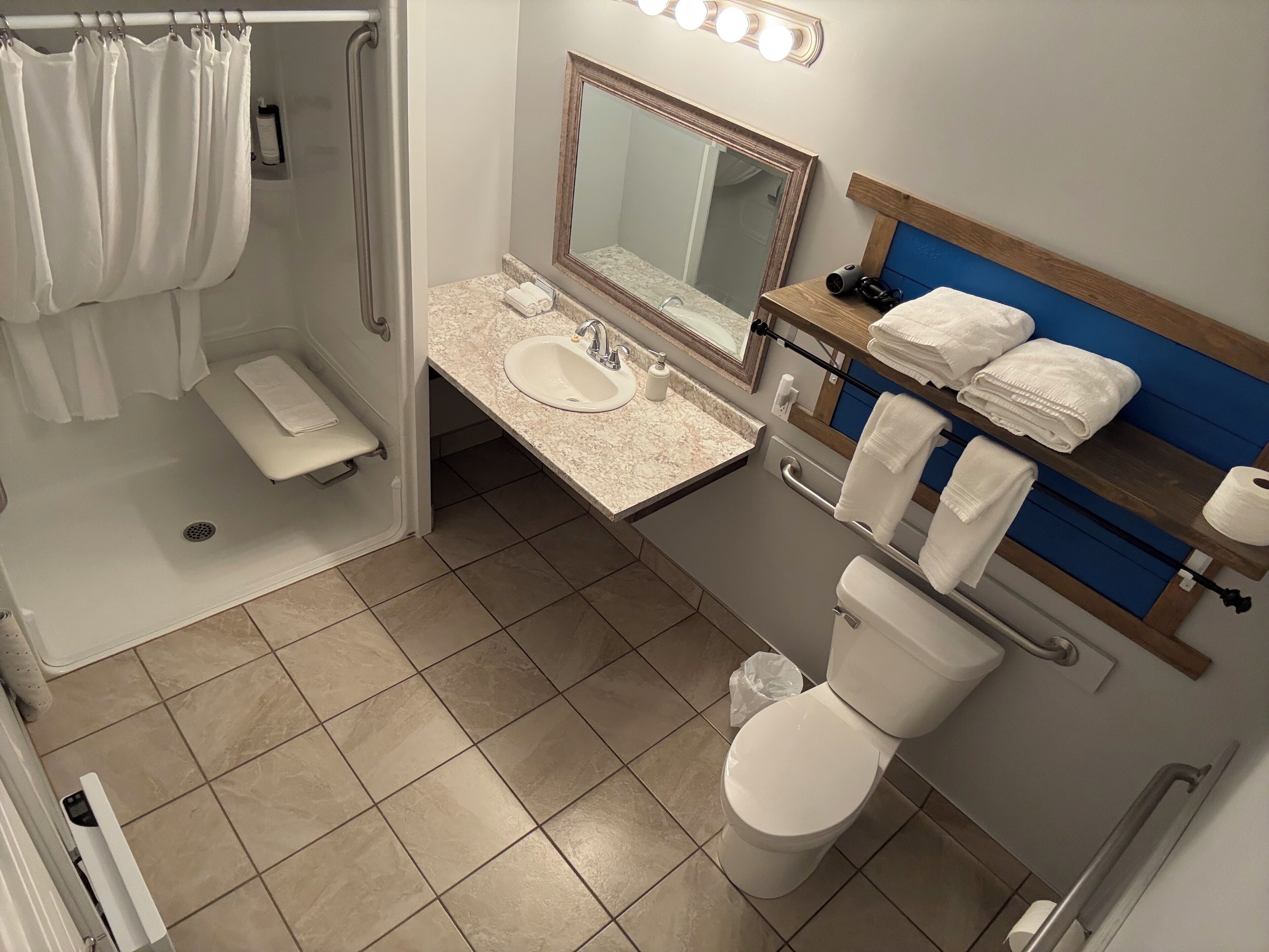 Une salle de bain équipée d’une douche, d’un lavabo, d’un miroir et de toilettes.