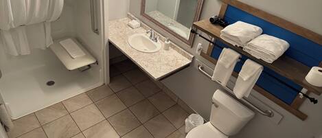 Une salle de bain équipée d’une douche, d’un lavabo, d’un miroir et de toilettes.